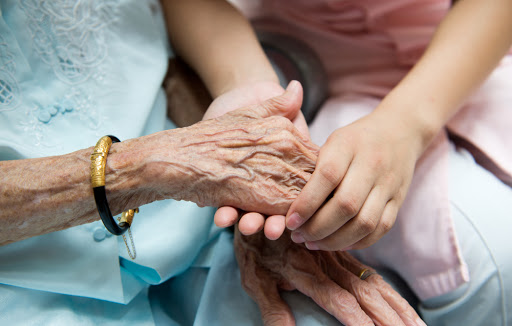 Young girl&rsquo;s hand touches and holds an old woman&rsquo;s wrinkled