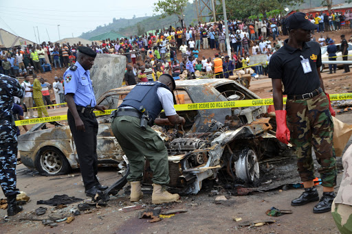 NIGERIA, Abuja : Nigerian security personnel inspect the site of a blast at Nyanya bus station