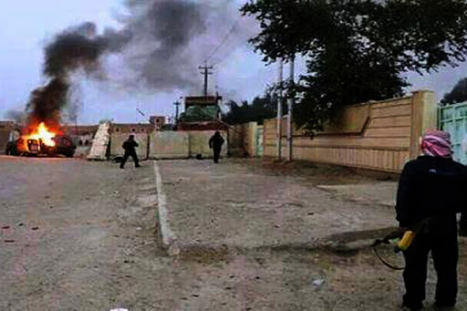 IRAQ, Mosul : A picture taken with a mobile phone shows an armed man watching as a vehicle is seen in flames