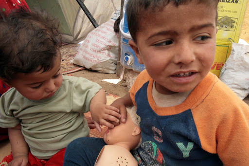 Iraqi children play at the entrance of their family&rsquo;s tent at a camp for refugees