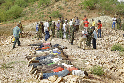 Members of the military gather near the bodies of some of the victims of an attack on quarry workers near the town of Mandera, northern Kenya