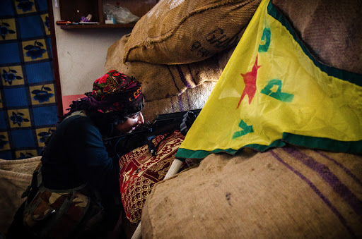 Female fighter of the Syrian Kurdish People&rsquo;s Protection Units with the Kurdish flag