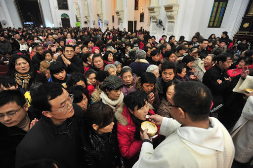 Chinese worshippers receive the Eucharist from a priest