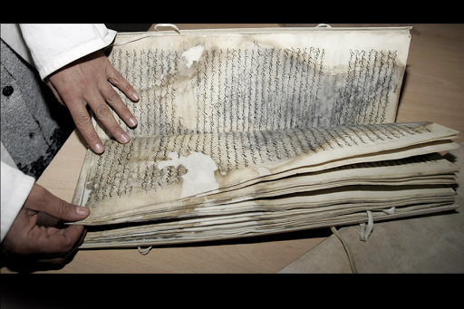 An Iraqi specialist inspects the damage of a manuscript