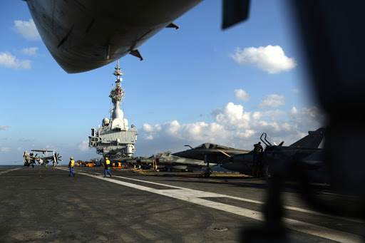 French Navy Rafale fighter jets (R) and a HawkEye reconnaissance plane (L) sit onboard the French Navy aircraft carrier Charles de Gaulle operating in the Gulf on February 23, 2015