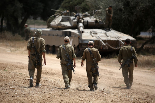 Israeli soldiers walk towards a Merkava tank &#8211; AFP &#8211; fr
