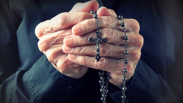 Hands of an elder woman holding a rosary