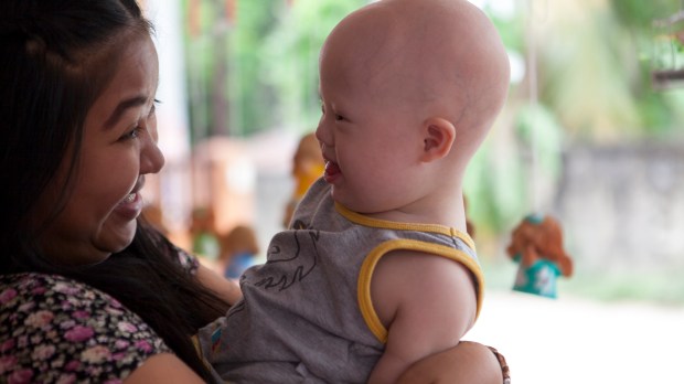 Gammy, le bébé trisomique abandonné à sa naissance par le couple australien Farnell à sa mère porteuse (Pattaramon Chanbua), avec cette dernière dans la nouvelle maison familiale à Chonburi (Thaïlande) le 23 avril 2015