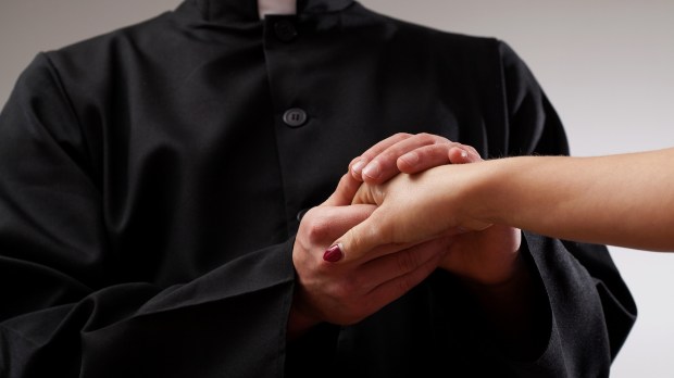 Good priest supporting believer and holding her hand