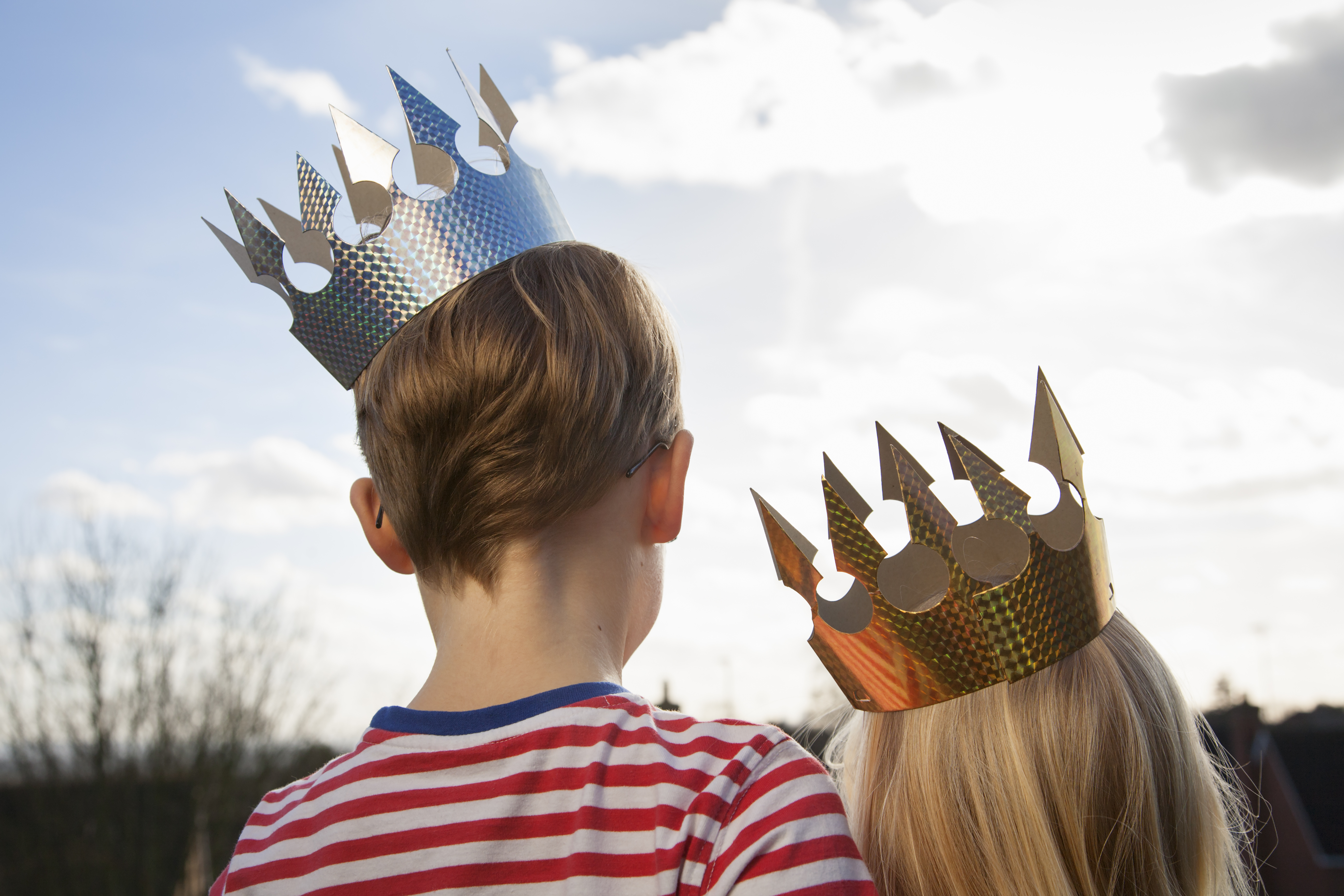 Two children in fancy dress, wearing crowns.