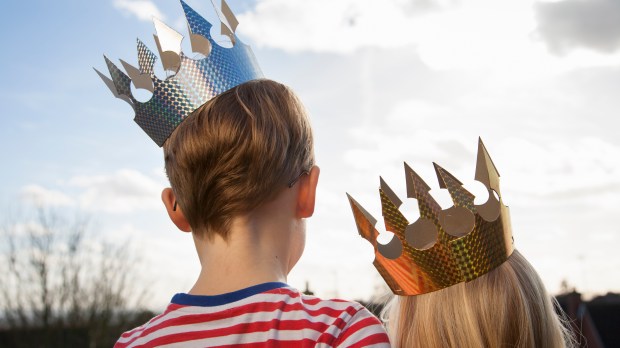 Two children in fancy dress, wearing crowns.