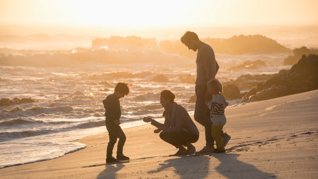 Happy young family enjoying on the beach at sunset