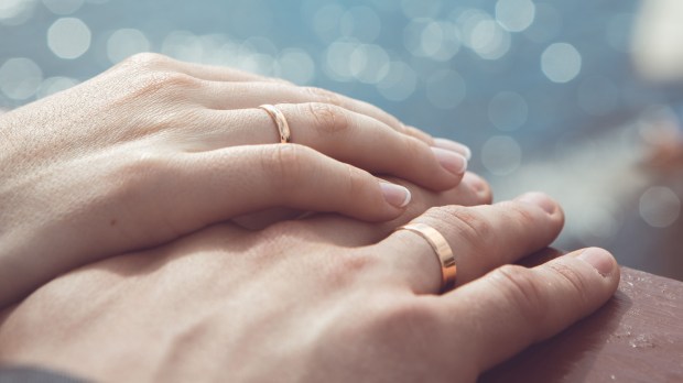 Holding Hands with wedding rings on the background of sea and sun &#8211; shutterstock_167534945 HERO