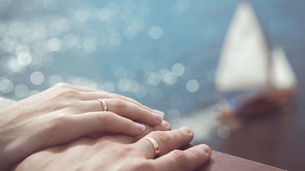 Holding Hands with wedding rings on the background of sea and sun &#8211; shutterstock_167534945