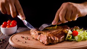 eating stake from plate with fork and knife man hands – shutterstock_487799251