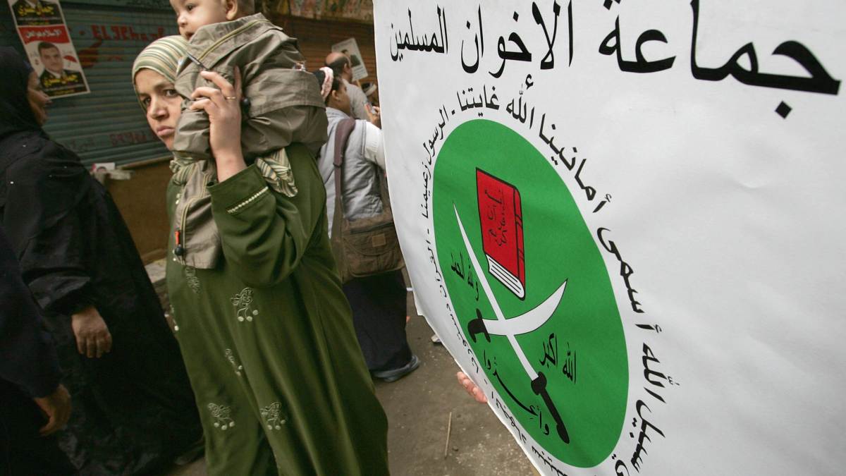 Une femme égyptienne porte son enfant pendant la campagne politique à proximité des bureaux de vote au Caire, le 09 novembre 2005. Derrière elle est brandit l’étendard des frères musulmans, qui protestaient alors contre le parti au pouvoir d’Hosni Moubarak, qu’ils accusaient de fraude de masse pour les élections. © AFP PHOTO / CRIS BOURONCLE