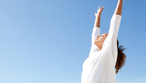 Jeune femme respirant les bras en l'air