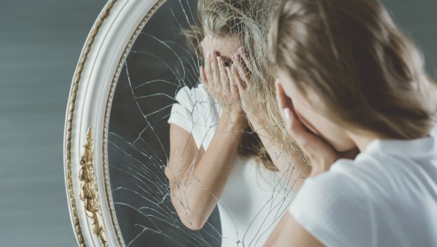 Jeune fille complexée devant un miroir brisé
