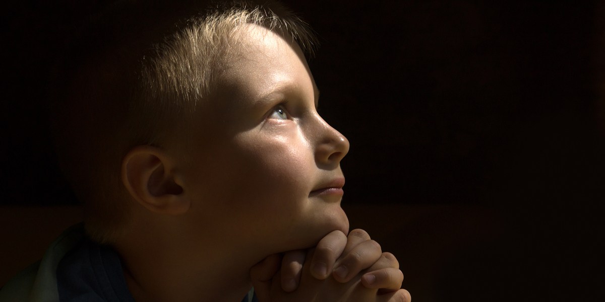 web3-young-child-praying-dark-background-oksana-mizina-shutterstock_303404972