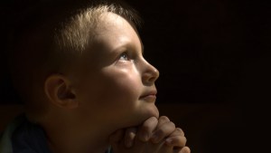 web3-young-child-praying-dark-background-oksana-mizina-shutterstock_303404972
