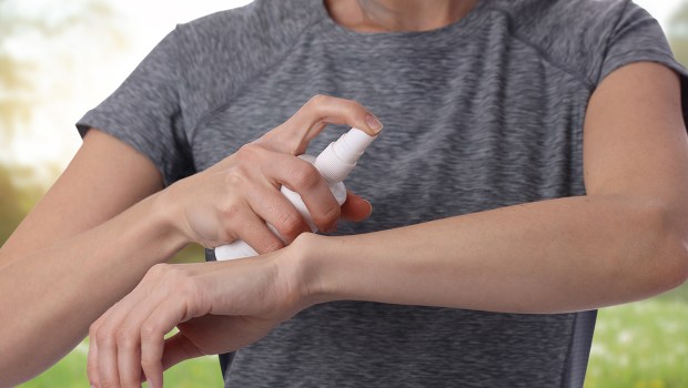 FEMME METTANT DU SPRAY ANTI MOUSTIQUE