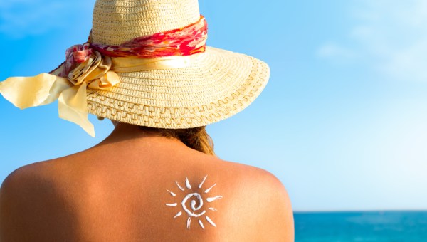 FEMME AVEC DE LA CREME SOLAIRE ET UN CHAPEAU