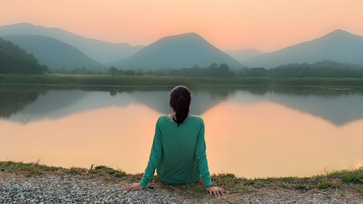 WEB3 WOMAN ALONE SOLITUDE MOUNTAINS LAKE SUNSET SILENCE Shutterstock