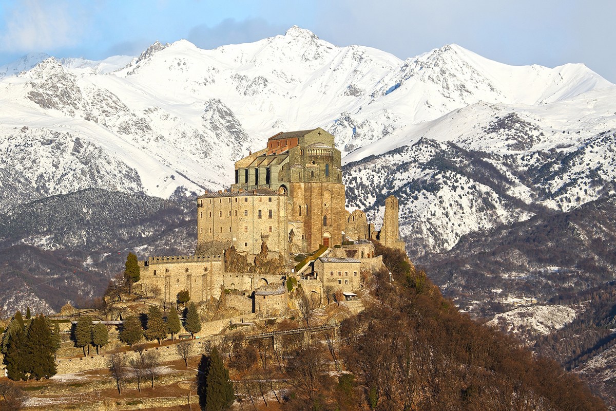 WEB – CUP001 – The Sacra di San Michele, the symbol of the Italian region of Piedmont, stands in the dawn. In the background are visible mountains of the Val di Susa – shutterstock_640285153