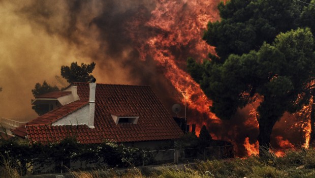 A house is threatened by a huge blaze during a wildfire in Kineta, near Athens, on July 23, 2018. More than 300 firefighters, five aircraft and two helicopters have been mobilised to tackle the "extremely difficult" situation due to strong gusts of wind, Athens fire chief Achille Tzouvaras said. / AFP PHOTO / VALERIE GACHE