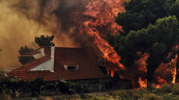 A house is threatened by a huge blaze during a wildfire in Kineta, near Athens, on July 23, 2018. More than 300 firefighters, five aircraft and two helicopters have been mobilised to tackle the "extremely difficult" situation due to strong gusts of wind, Athens fire chief Achille Tzouvaras said. / AFP PHOTO / VALERIE GACHE