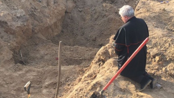 Cardinal Konrad Krajewski prays at a mass grave in Ukraine