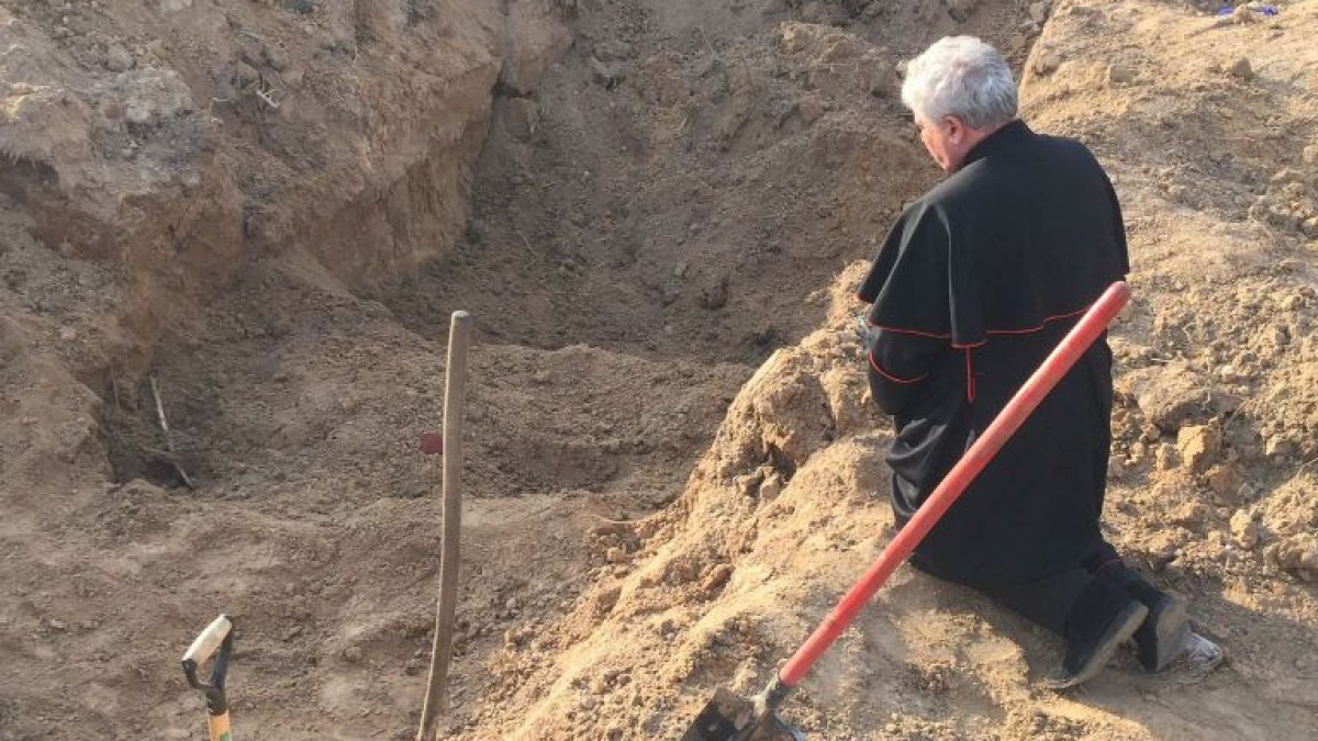 Cardinal Konrad Krajewski prays at a mass grave in Ukraine