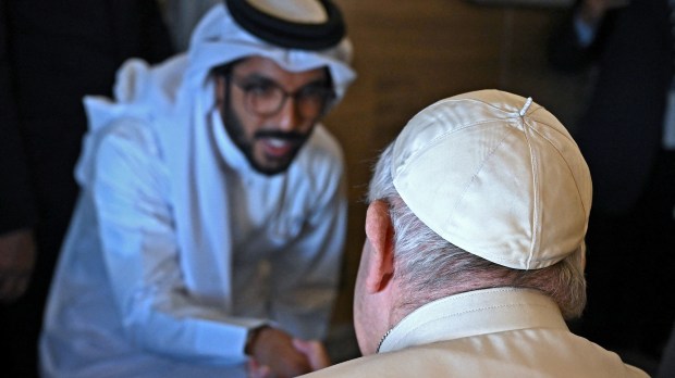 Pope-Francis-shakes-hands-with-a-journalist-from-his-seat-aboard-the-plane-from-Rome-to-Manama-AFP