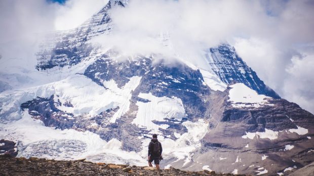 Man versus mountain. Man staring in awe of a mountain