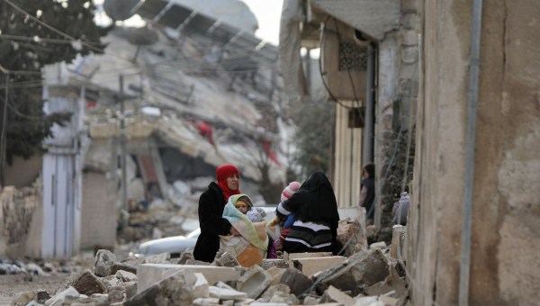 Syrian women and children sit wrapped in blankets outside collapsed buildings on February 7, 2023, in the town of Jandairis, in the rebel-held part of Aleppo province, as search and rescue operations continue following a deadly earthquake. - The death toll from the massive earthquake that struck Turkey and Syria rose above 8,300, official data showed, with rescue workers still searching for trapped survivors. (Photo by Bakr ALKASEM / AFP) - EN_01553763_1096.jpg