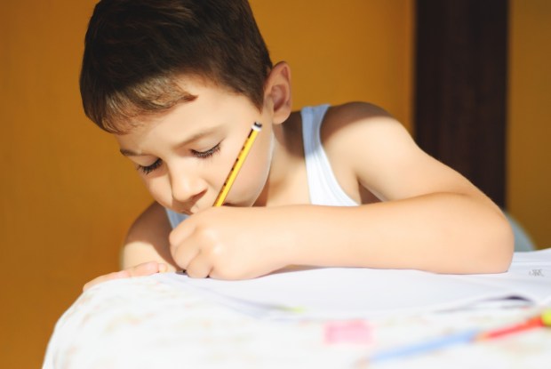 Chłopiec odrabia lekcje, pisząc lewą ręką