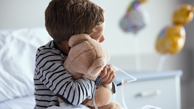 Niño enfermo en el hospital con un osito de peluche