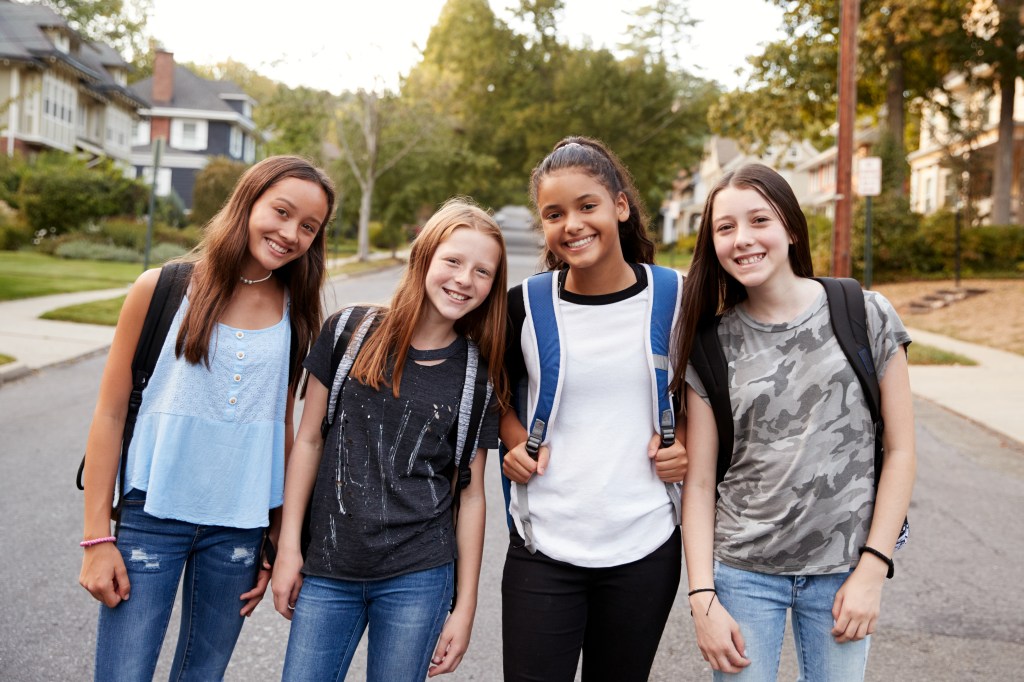 Teen girls on the way to school looking to camera, close up