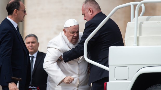 Pope Francis is helped get up the popemobile car as he leaves