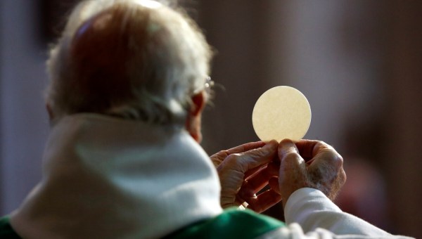 Ksiądz odprawiający Mszę unosi w dłoniach konsekrowaną hostię przed Komunią świętą