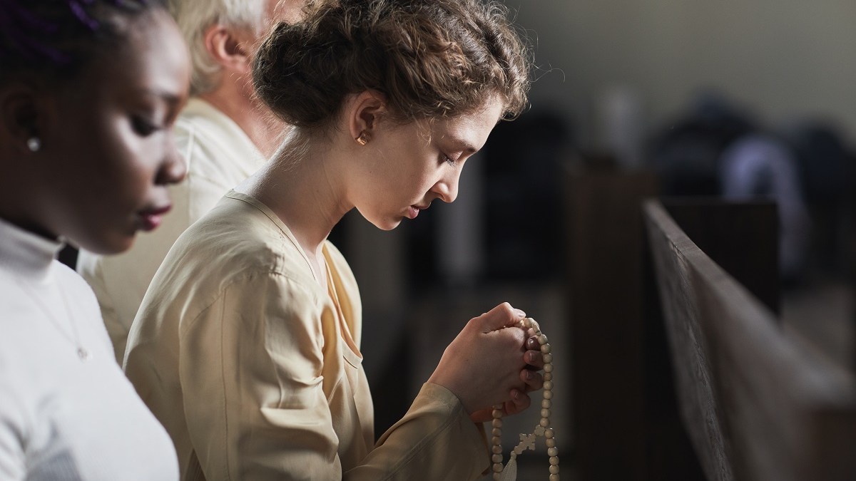 Young adult Catholic praying in church
