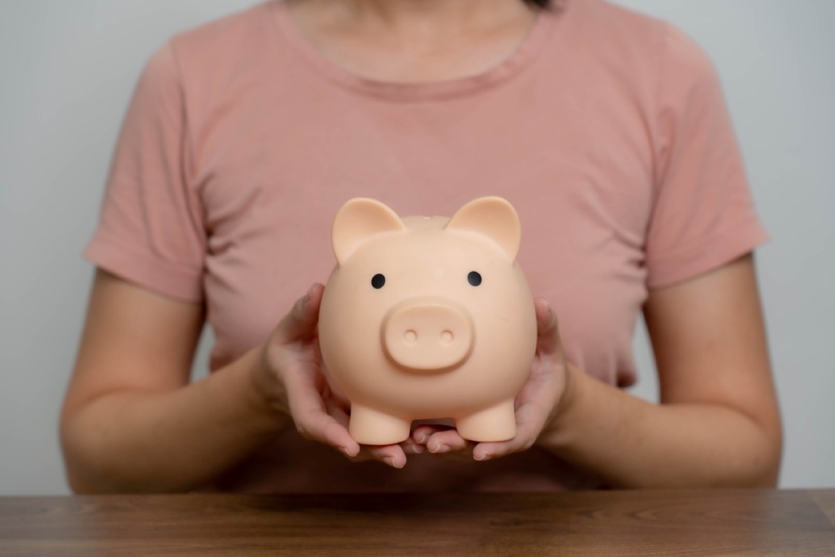 Woman saving money in a pink piggy bank