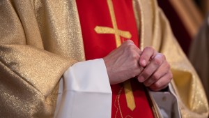 Katolicki ksiądz trzyma złożone ręce
