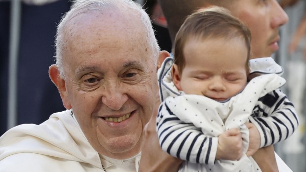 A baby is held up to Pope Francis as he arrives at the Velodrome stadium in his popemobile for a mass in the southern port city of Marseille