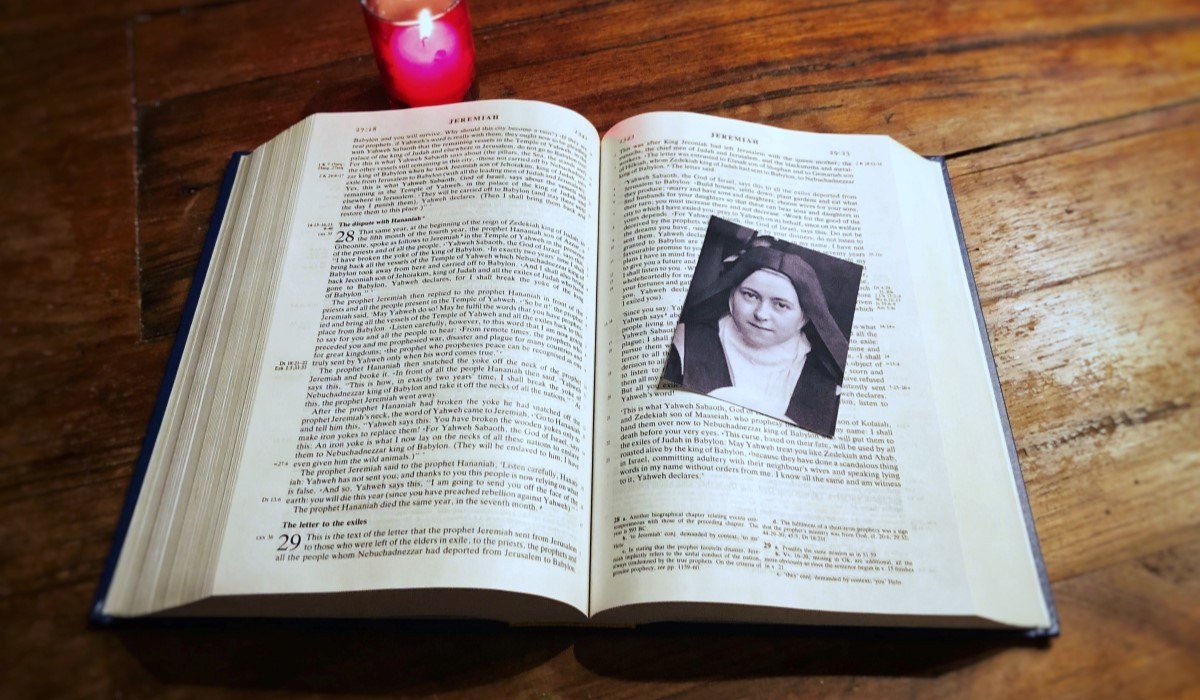 Photo of St. Thérèse of Lisieux on Bible with red candle