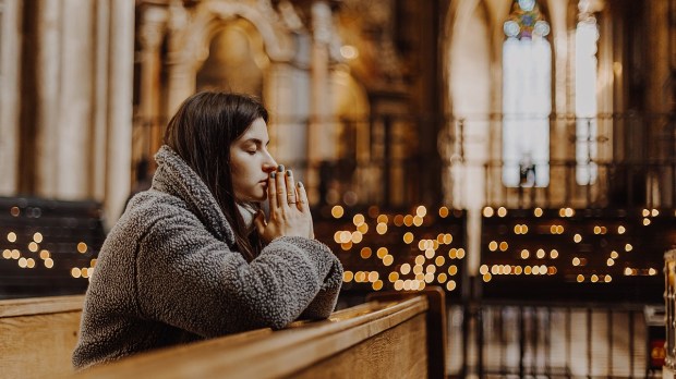 Woman praying in church with candels