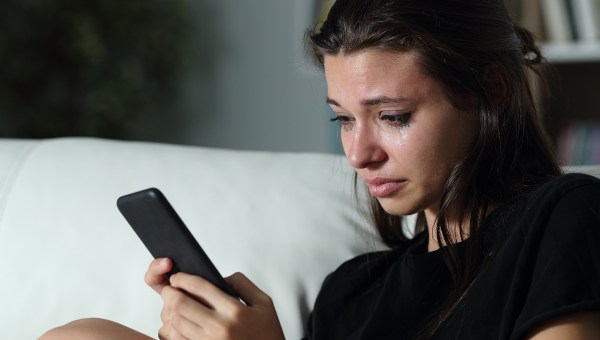 Woman watching phone tears