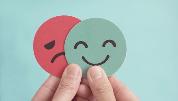 Manos-con-cara-triste-escondiendose-detras-de-cara-feliz