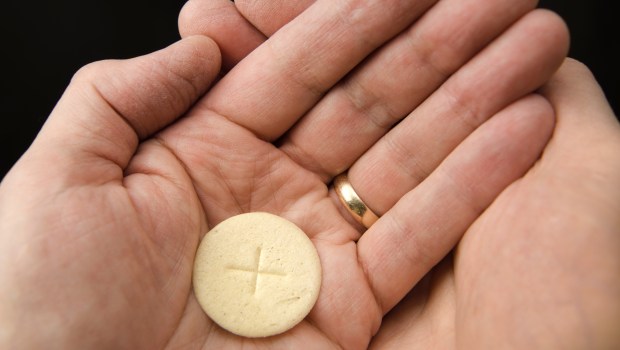 | wedding ring,hands,body of christ,cupped,communion,mass,sacrament,body,gluten-free,hold,holding,receiving,christian,host,oak,wheat,man,relief,sacred,table,eucharistic,bread,holy,roman catholic,black,sacrifice,mass consecrated,religion,chalice,eucharist,wafer,redemption,the body of christ,god,jesus christ,married,wine - shutterstock_1269336400.jpg