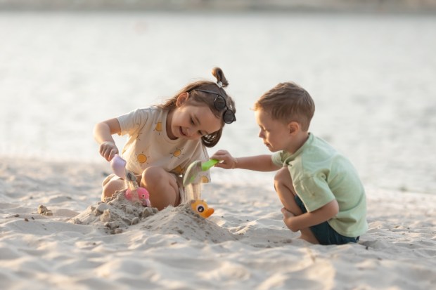 Children boy and girl playing on the beach on summer holidays